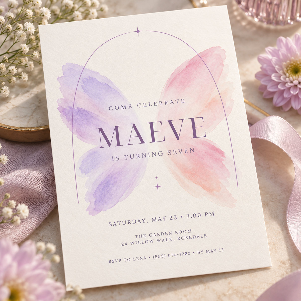 Lilac and pink wings invitation angled on soft lilac fabric