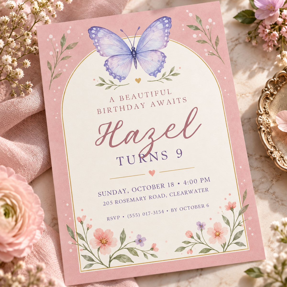 Pink arch butterfly birthday invitation angled on pink fabric