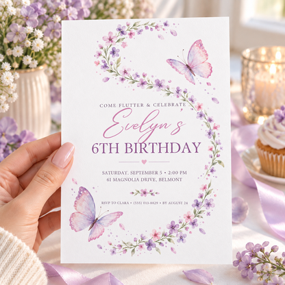 Hand holding a white invitation with a curving lavender floral wreath and pastel butterflies