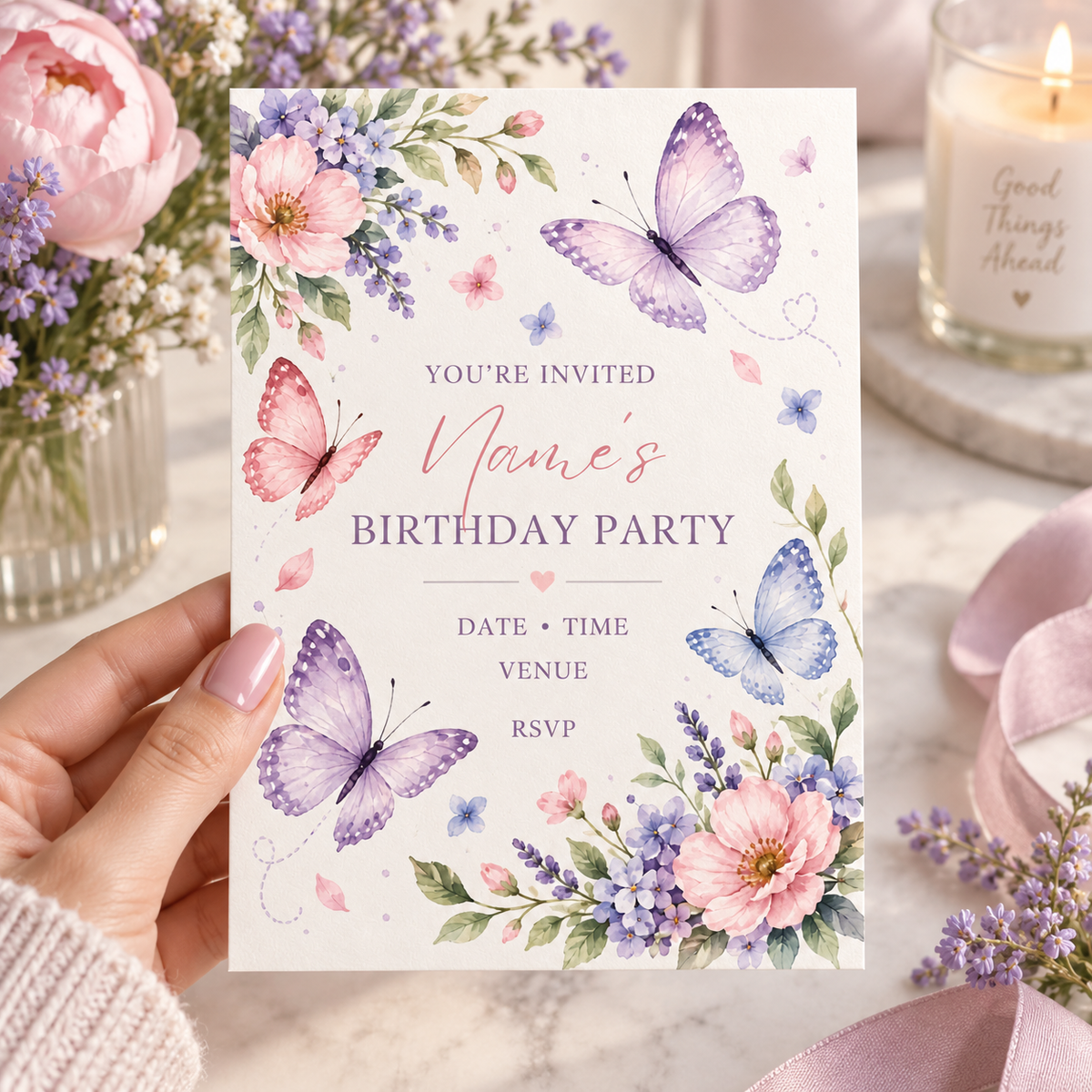 Hand holding a cream butterfly invitation with peony corners and lilac, pink and blue butterflies