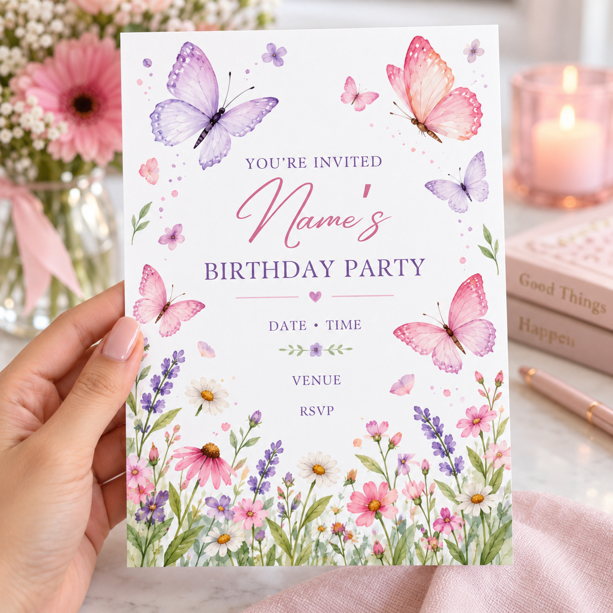 Wildflower butterfly birthday invitation held beside a candle and stacked books
