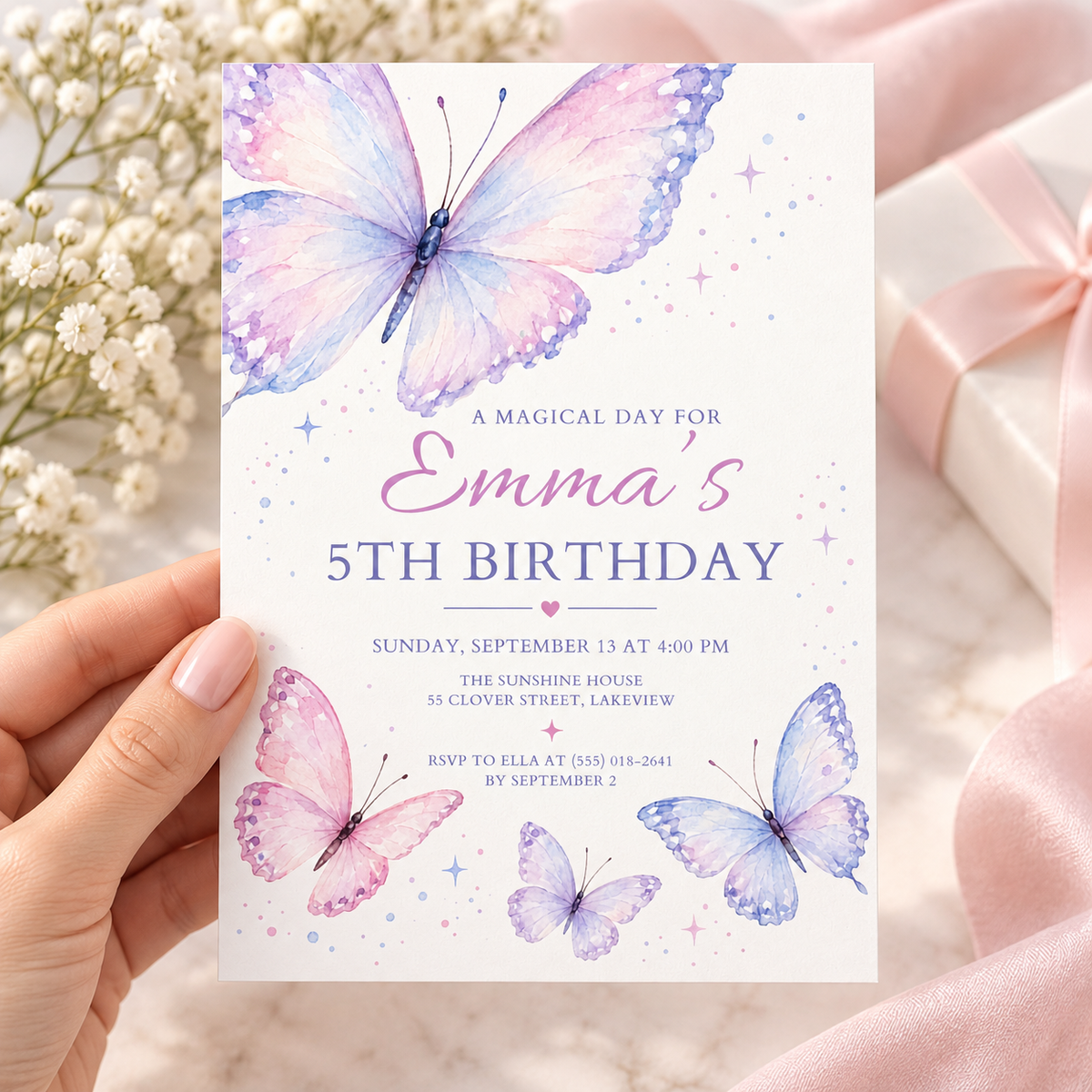Hand holding a pastel lavender butterfly birthday invitation with script lettering