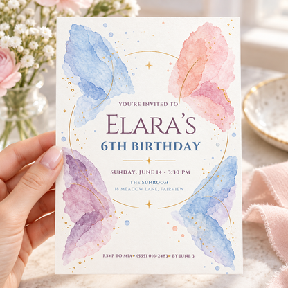 Hand holding a watercolor butterfly wings birthday invitation in blue and pink